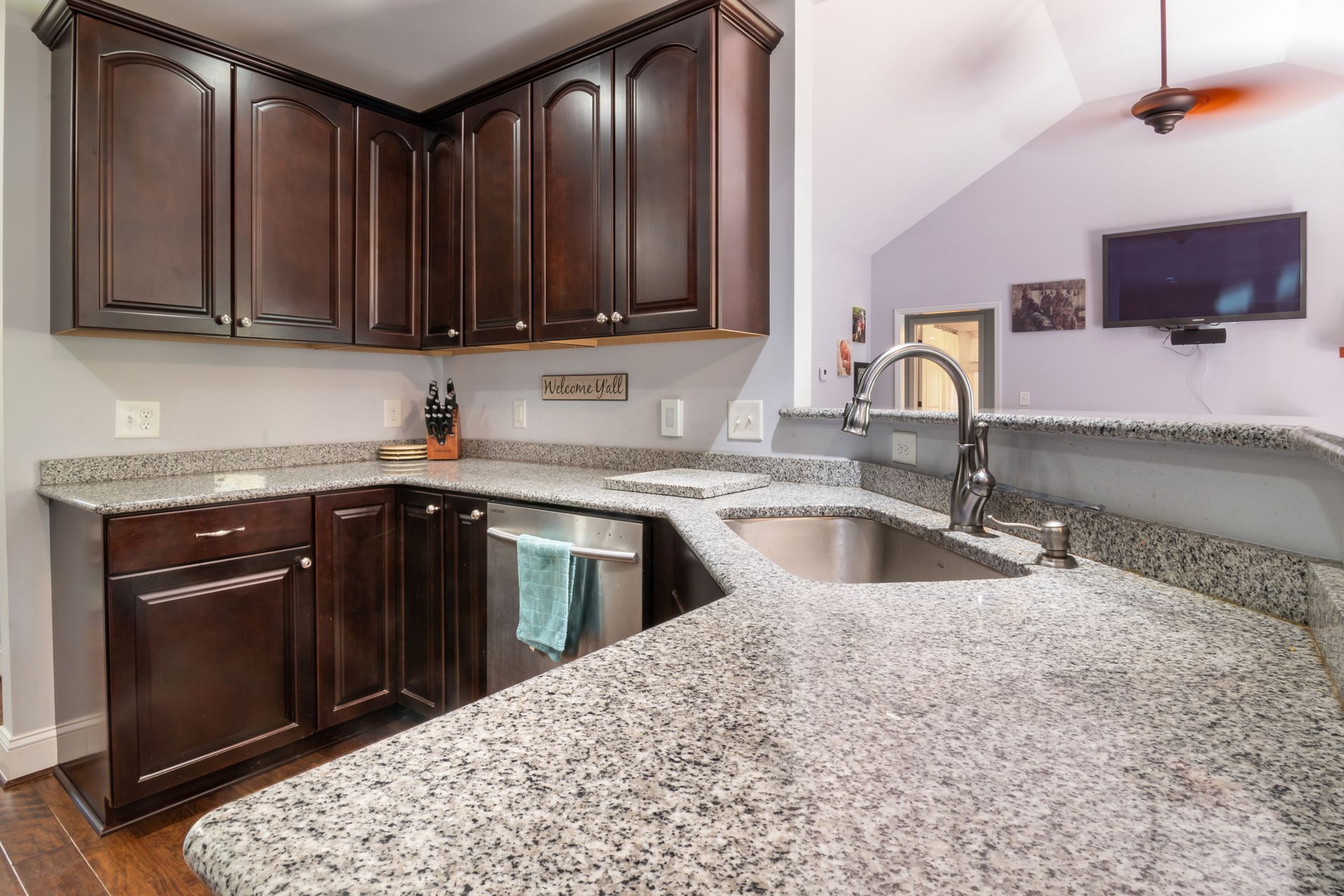 Contemporary kitchen design featuring granite countertops, dark wooden cabinets, and stainless steel appliances.